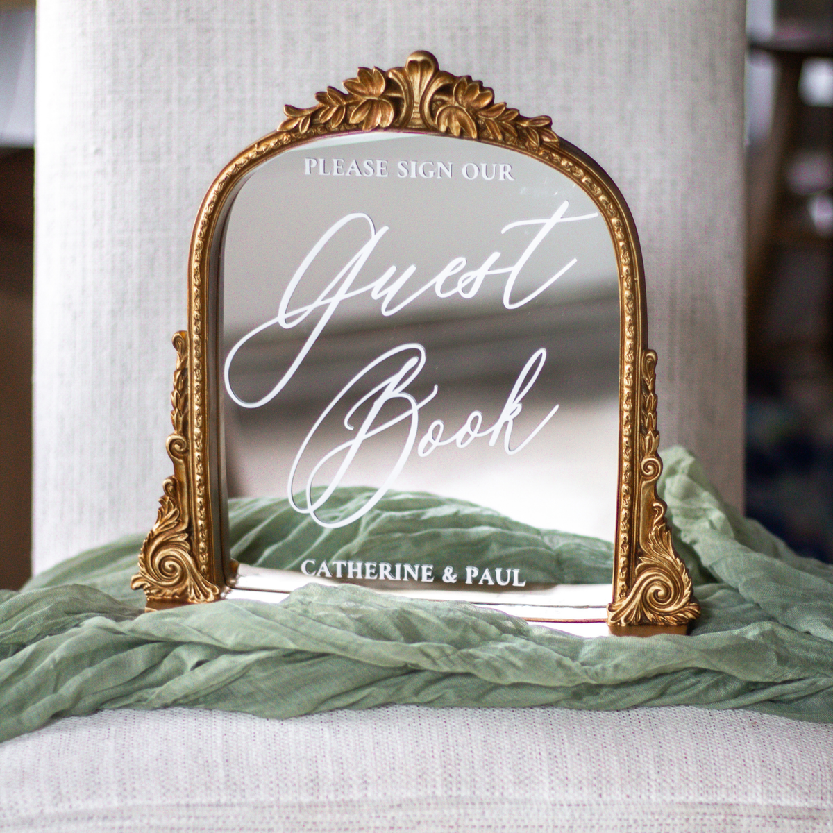 Elegant wedding guest book mirror sign with gold frame and calligraphy script at wedding reception.